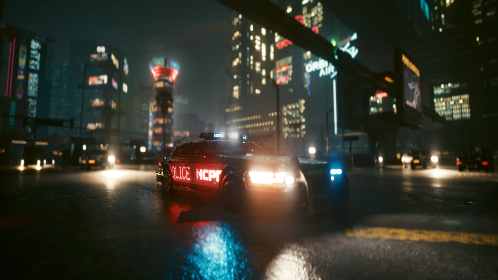 A Villefort Cortes with its headlights on and POLICE NCPD lit red along its side, on a wet street at night with the city’s towers behind
