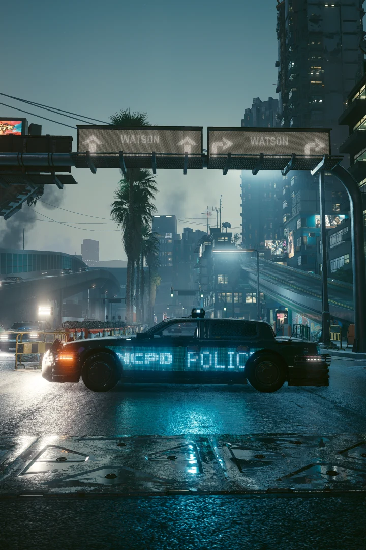 A Villefort Cortes, NCPD POLICE lit in blue along its side, stopped on a wet road beneath overhead signs pointing to Watson