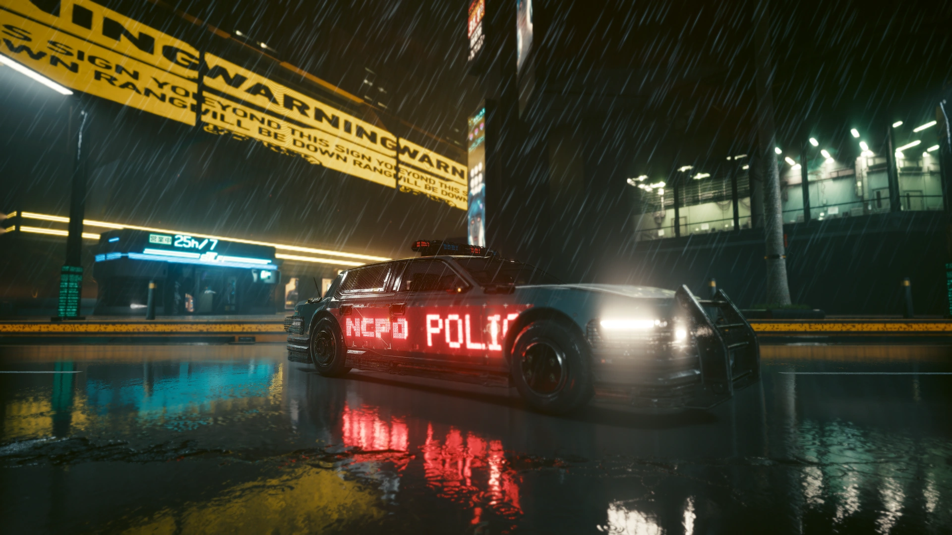 A patrol car stopped in the rain beneath a yellow WARNING gantry, NCPD POLICE lit red along its side